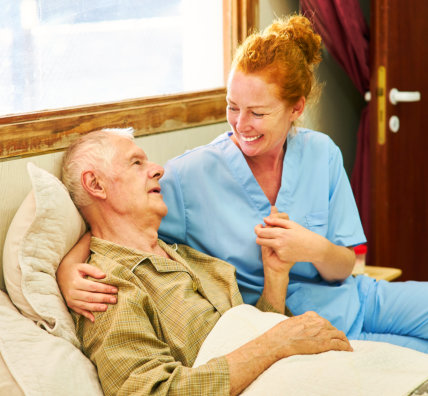 smiling caregiver holding senior man's hand